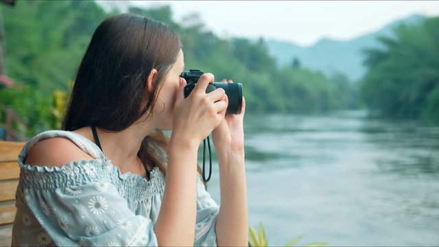 Young woman tourist looking at camera and taking pictures of beautiful landscape