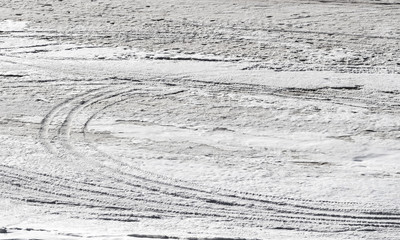 Traces of a car on the snowly river bank in winter.