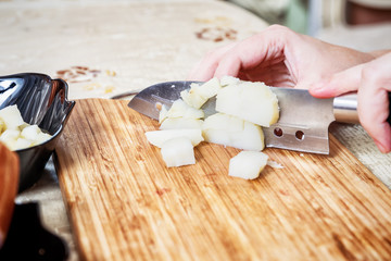Woman's hand with a knife cutting the boiling potatoes