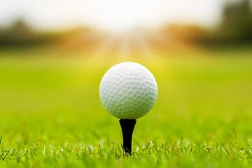 Deurstickers Close-up van golfbal op tee in gras met zon. © Nischaporn