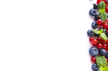 Ripe blueberries, blackberries, strawberries, red and black currants on white background. Mix berries and fruits at border of image with copy space for text. Top view. 