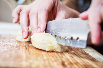 Woman's hand with a knife cutting the boiling potatoes
