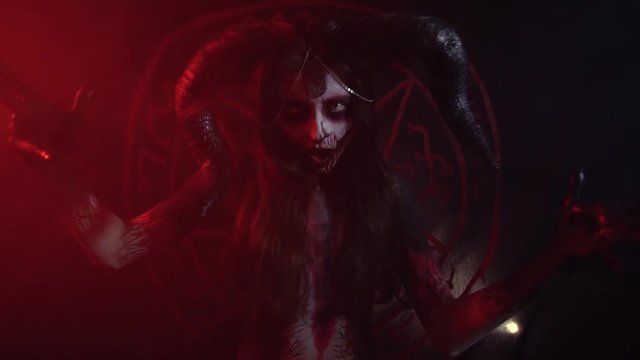 The devil laughs inside the girl in red light, body painting