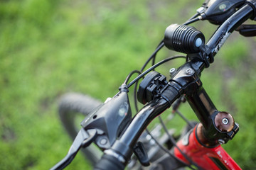 Fototapeta premium Mountain bike of red color with a black rudder on green grass