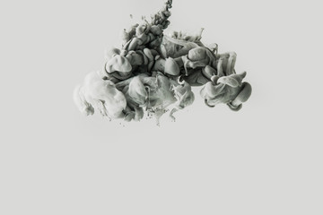 close up view of smoke or mixing light gray and black paints splashes in water isolated on gray
