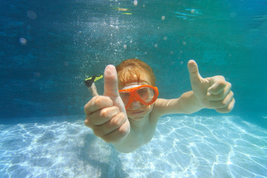 happy little boy swim underwater with thumbs up