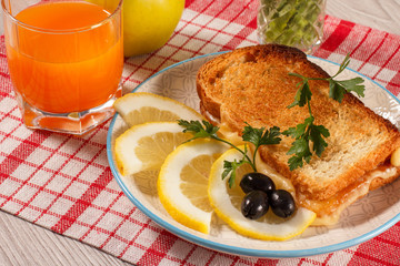 Good and delicious food and beverages for breakfast. Toast with butter and cheese, slices of lemon and olives on plate