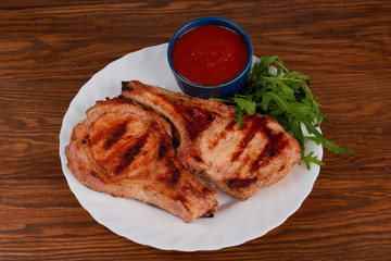 Pork grilled with fresh arugula leaves on a white plate. Top vie