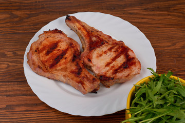 Pork grilled with fresh arugula leaves on a white plate. Top vie