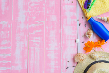 Beach accessories including sunglasses, hat beach, shell, sunscreen and flower on bright pink pastel wooden background for summer holiday concept.