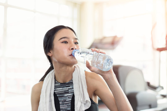 Pretty sporty young asian woman drinking water after sport training workout