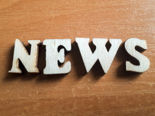 The word 'news' made of wooden letters. wood inscription on a keyboard background