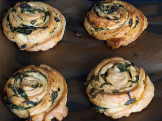 Buns of puff pastry with spinach and garlic on a baking tray for baking. Homemade pastries with greens.