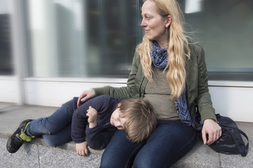 Madre cuidando a su hijo mientras descansa sobre ella. 