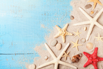 Summer travel background from seashell, starfish and sand on blue table top view.