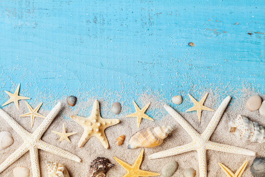 Composition from seashell, starfish and sand on blue table top view.