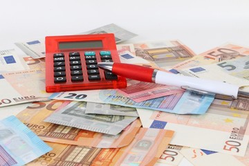 a heap of different euros with a red calculator and a pen lying in the studio