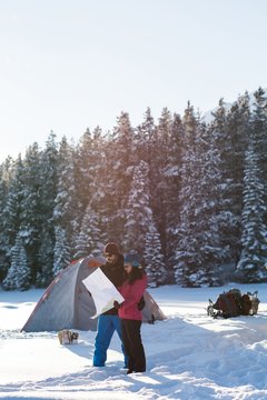 Couple looking at map in snowy landscape