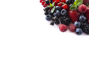Mix berries and fruits at border of image with copy space for text. Ripe blackberries, blueberries, strawberries, currants and raspberries on white background. Top view. 