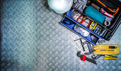 Top view of tools box and helmet on checkered plate background in workshop. Service tools set. Home...
