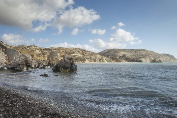 corner of the rocky beach of Venus on the island of Cyprus against the backdrop of mountains and blue sky