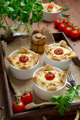 Ramekins with tasty chicken and bacon quiche on wooden board