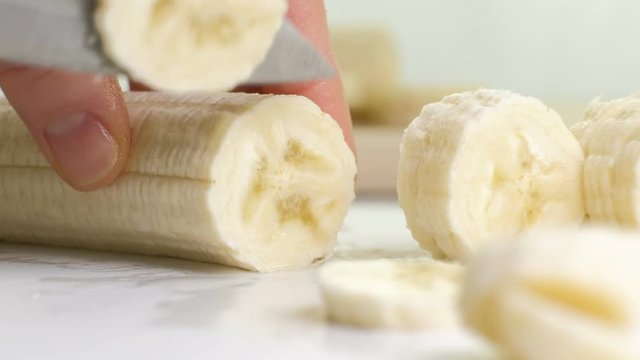 Slow motion macro closeup of chopping fresh banana with knife