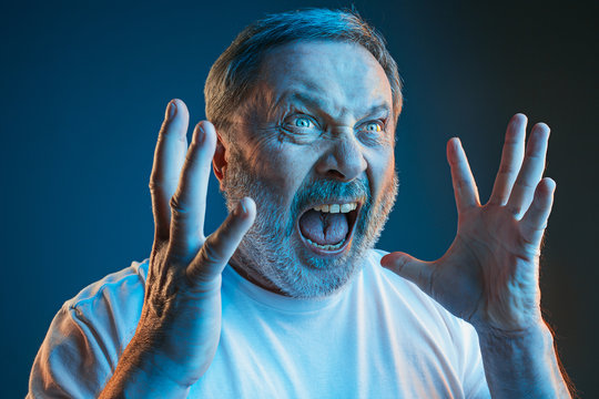 The senior emotional angry man screaming on blue studio background