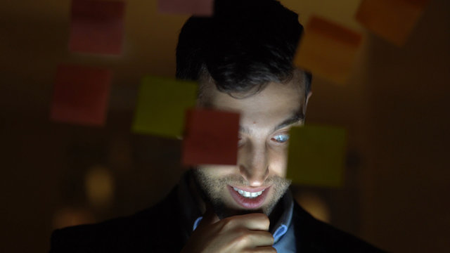 Business man working late building new ideas with sticky note paper on window