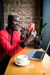 Young afro american man speak with friends via video call from phone in cafe