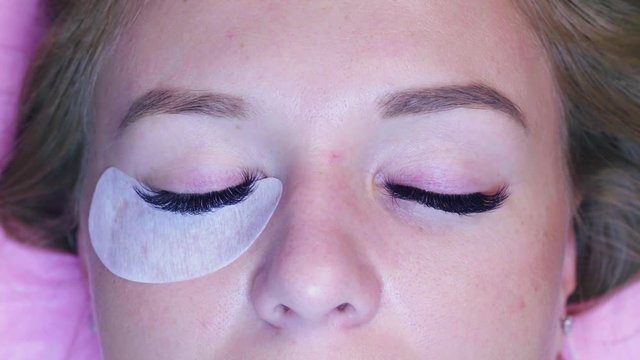 Close up woman face. Eyelash extension procedure. Cosmetologist removing eye patches