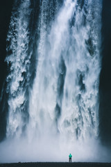 Fototapeta premium Wycieczkowicz przy gigantycznym wodospadzie Skogafoss na Islandii