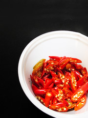 Chopped red chili pepper in White bowl on black background.