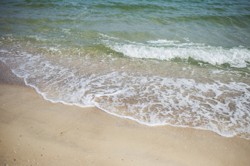 Fototapeta na wymiar Beautiful tropical beach in morning sunlight. Charming foamy sea waves and yellow sand texture.