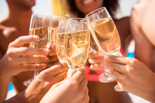 Diversity international entertainment season festive  event cheerful joyful smiling victory win tourism travel concept. Close up  cropped photo of people's hands clinking glasses full of champagne