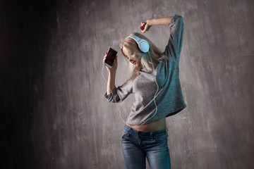 Dancing attractive woman listening to music in the mobile app. Girl music lover.