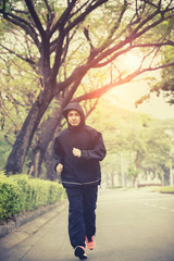 young man wearing hood jacket running on urban street