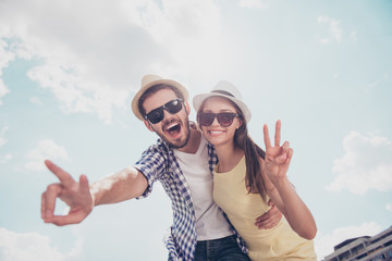 Bottom view low angle of cheerful positive joyful stylish trendy funny attractive couple in caps,...