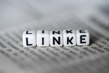 Word LINKE formed by wood alphabet blocks on newspaper german party politics