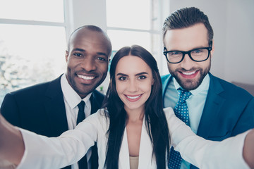 Self portrait of stylish successful, professional trio, beautiful girl shooting selfie in two hands...