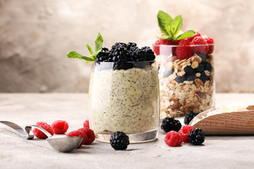 Healthy berry chia pudding in a jar with scattered fruit isolated on rustic grey background