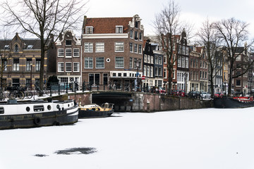 Obraz premium Stunning view of Amsterdam canals and house boat frozen with snow during the cold wave in February 2018 on a very cold winter day.