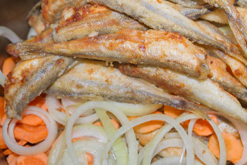 Fried fish smelt lies on the cut onion and carrot