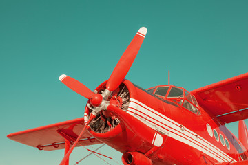 Red biplane on sky background. Close-up with engine and propeller