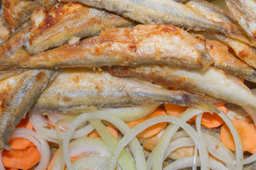 Fried fish smelt lies on the cut onion and carrot