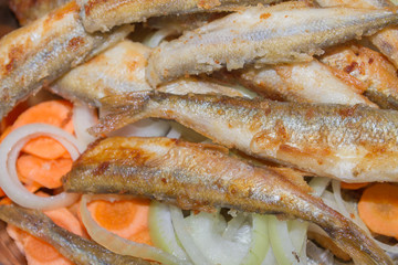 Fried fish smelt lies on the cut onion and carrot