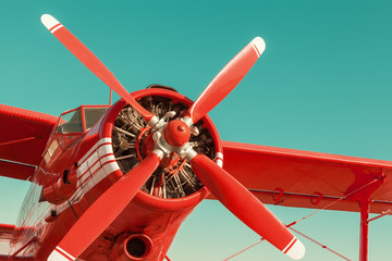 Red biplane on sky background. Close-up with engine and propeller - obrazy, fototapety, plakaty