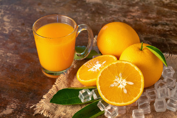 Fresh orange and a glass of orange juice on a wooden table background