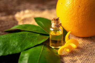 bottles with Essential Oil of orange peel and leaf on wooden table