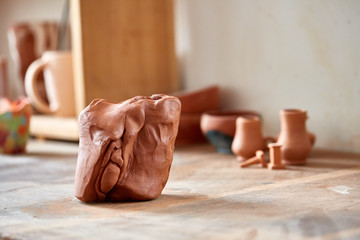 Large piece of red clay closeup on worktop at the potter workshop, close-up, shallow depth of field